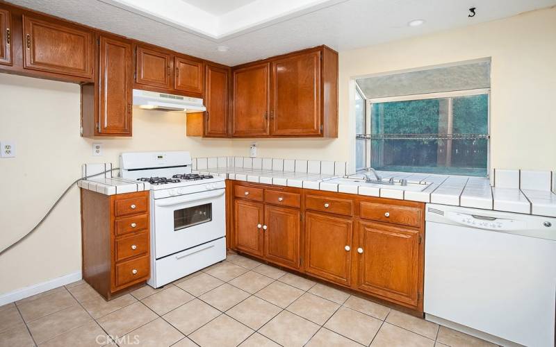 The cook in the family is going to truly appreciate the kitchen with its garden window, recessed lights, wood-grained cabinetry that reaches the ceiling, handy pantry, tile countertops, dual basin sink, Frigidaire gas range with ventilation hood, GE dishwasher, easy-care tile floors, and convenient breakfast bar.