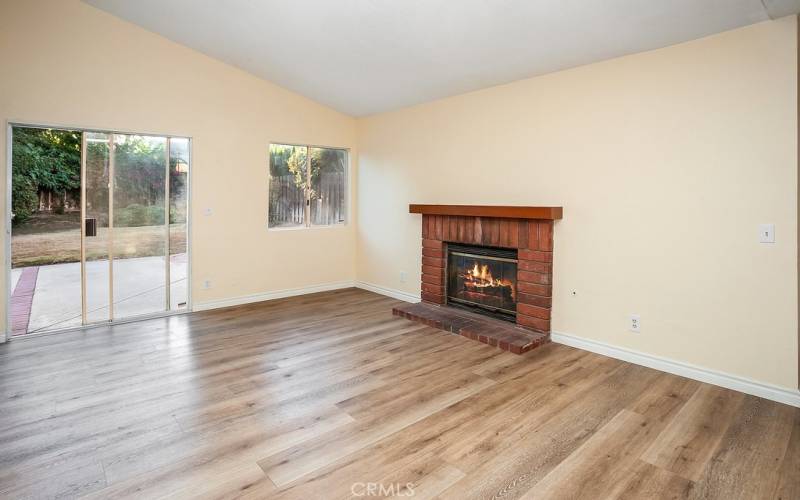 The family room is bathed in natural light from a multitude of windows and is enhanced by pitched ceilings, brick fireplace with mantle, sliding glass doors that lead to the backyard and rich wood-grained vinyl flooring.