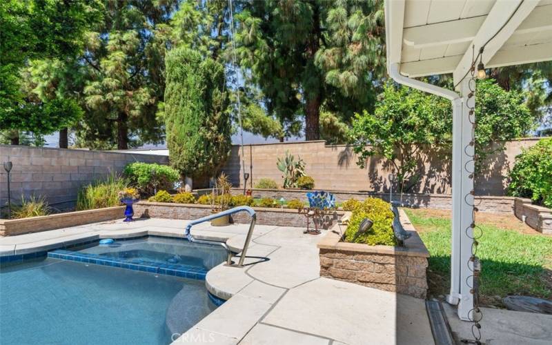 Inviting spa, lush lawn and flowerbeds for gardening.  A huge side yard, just to the right on the north side of the  lot, holds pool equipment and two very large storage sheds, conveniently out of sight behind a vine-covered archway.