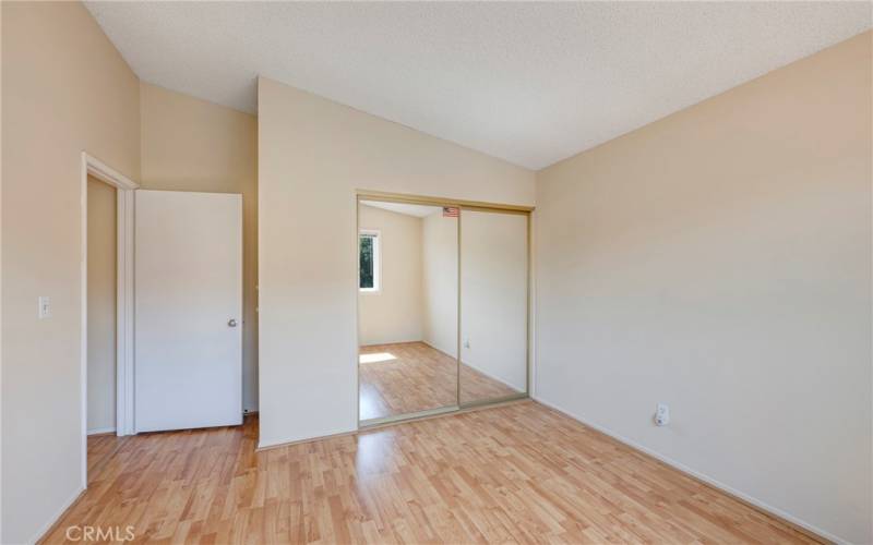 Secondary bedroom at end of catwalk has mirrored closet doors.