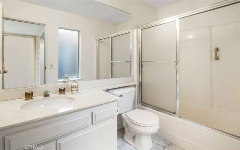 The guest bathroom with tub/shower enclosure, toilet and sink.