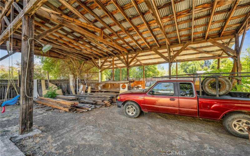 One of the original structures on the property is this spacious covered area; open on several sides, sits to front side of property.  Currently has lumber stacked underneath; lumber, childs swing, truck, some other personal items do not convey with property.