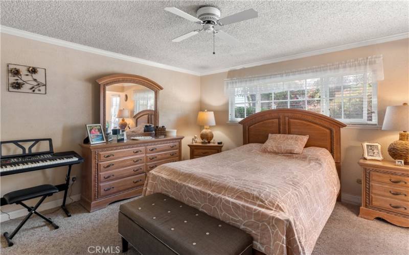 Large primary bedroom with crown molding, ceiling fan and window blinds!