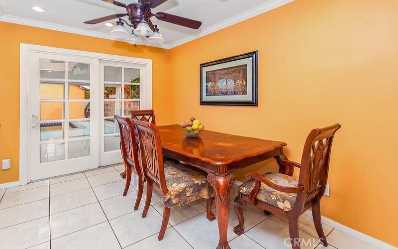 The dining room fittingly adjoins the kitchen and with its recessed lights, crown molding, lighted ceiling fan, tile floors, and sliding French door that leads to the backyard, it is perfect for any occasion.