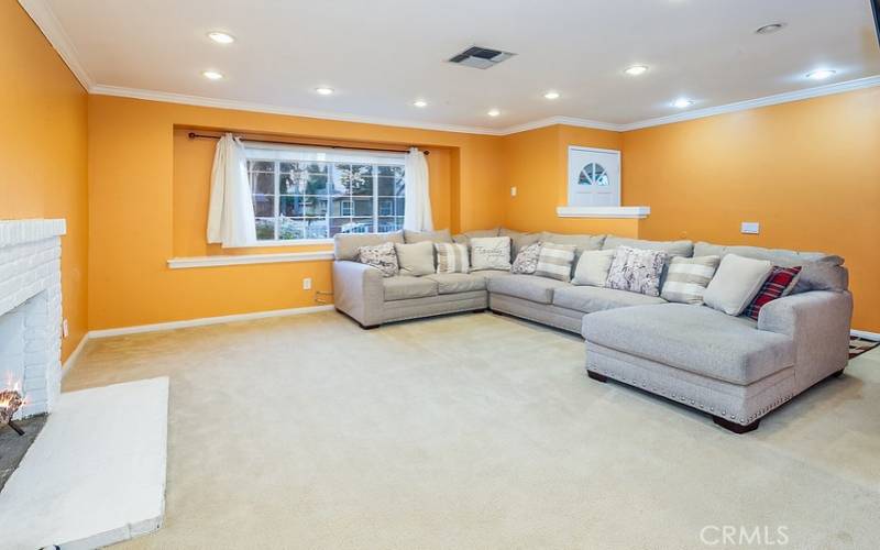 The family room is bathed in natural light from a multitude of windows and is enhanced by crown molding, a brick fireplace, and freshly cleaned wall-to-wall carpet.