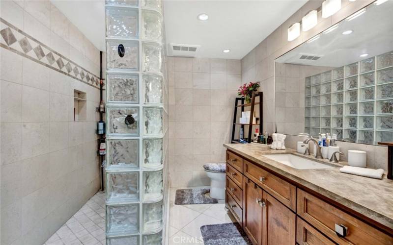 Remodeled and Expanded Primary Bathroom with Oversized Walk-In Shower, Glass Block Accent Wall, Granite Countertop, Floor-to-Ceiling Tile Walls