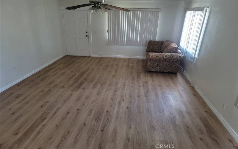 Spacious living room with front door and matching fine flooring.