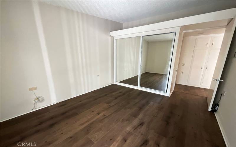 Master bedroom with mirrored wardrobe and attractive laminate wood flooring