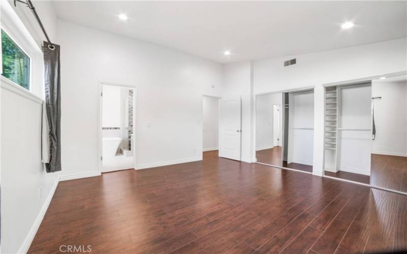 Primary bedroom with view of master bathroom in background. Two sets of mirrored closets