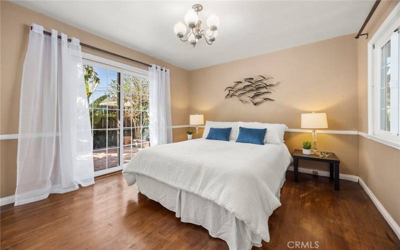 Bedroom 1 has original hardwood floors and sliding glass doors that lead to the side yard and pool.