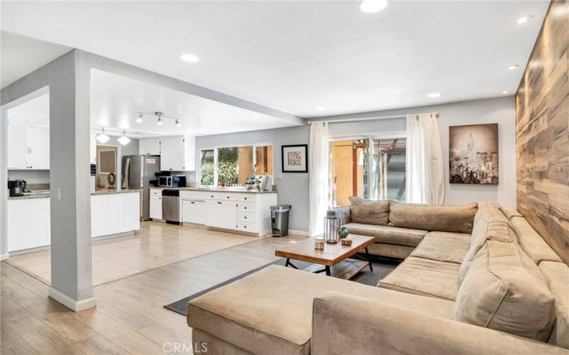 Expansive family room with recessed lights, designer wood-grained accent wall, sliding glass door leading to the backyard and rich wood laminate floors.