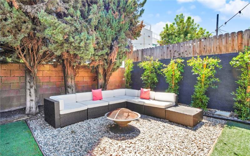 The private backyard will be a favorite entertainment destination with its towering privacy trees, artificial lawns, decorative fencing with rows of ficus trees, pergola covered patio with room for outdoor dining and barbecuing, and relaxing lounging area around the fire pit.