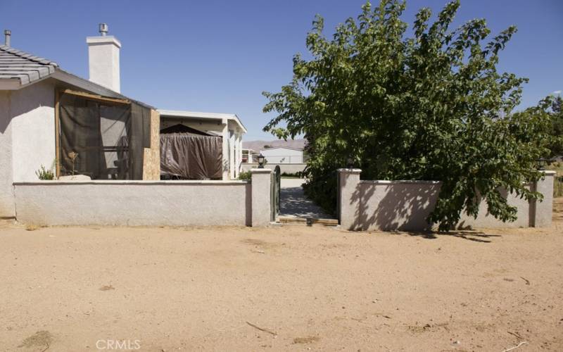 Gate separating the firepit area/patio from the empty land/baskeball court