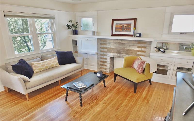 Living room view highlighting the built-in cabinetry, long mantel and the charming front of the home.