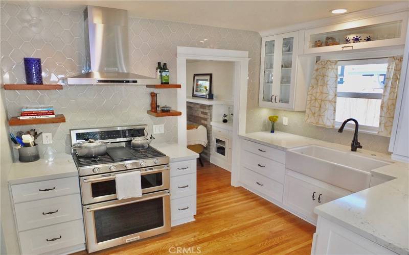 Stunning kitchen featuring a farmhouse sink, double ovens, a sleek range hood, and under-cabinet lighting for a touch of modern elegance