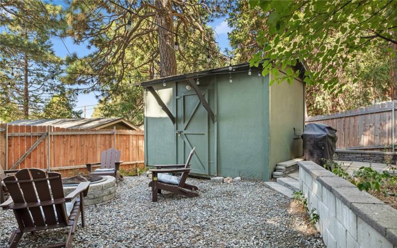 Fenced yard with storage shed and firepit.