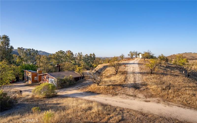 Dirt road runs from entrance on Lake Nacimiento Dr to detached studio and garage. Road up the hill leads to water storage tank