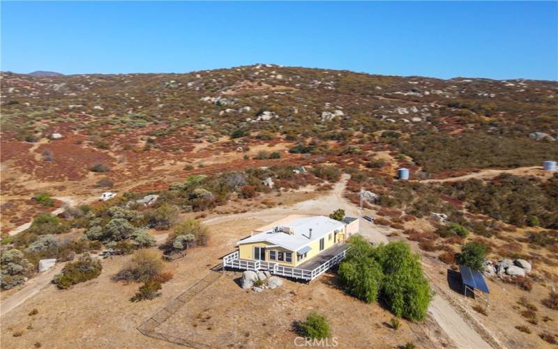 Ariel View of property looking East with view of solar panels and water holding tanks