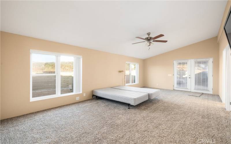 Primary bedroom with double door entry to back yard with block wall and covered patio