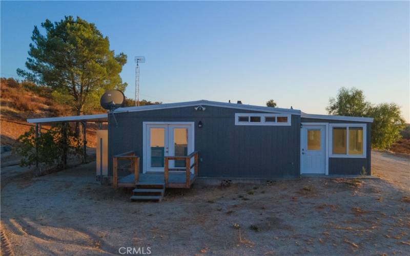 Back of home with double doors leading to primary bedroom and covered porch on back of the house.