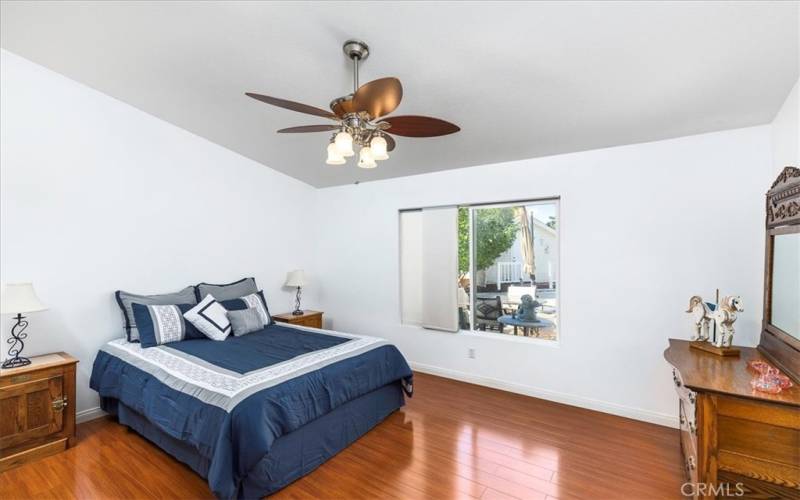 Primary bedroom with vaulted ceiling, wood laminate flooring and window with view to back yard.