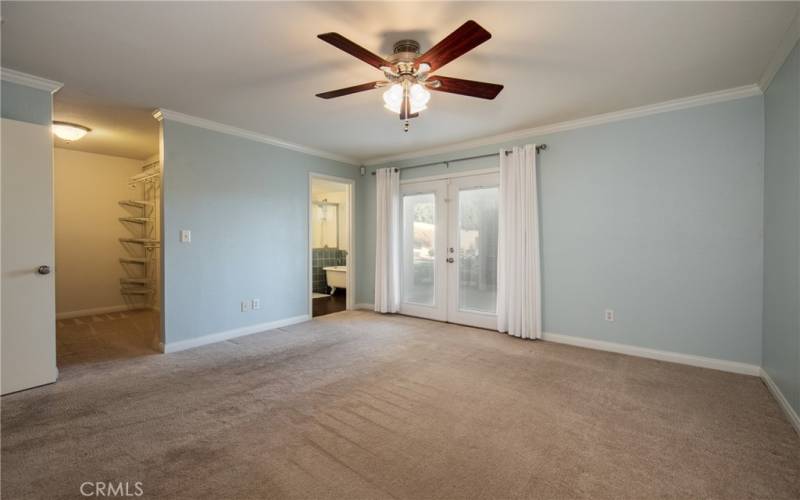 Primary bedroom with nice sized walk in closet and French doors opening up to outside covered patio.