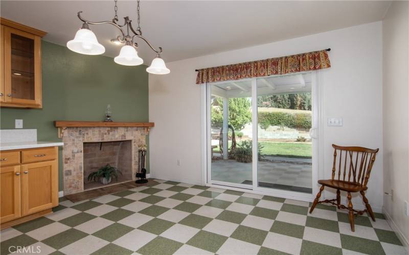 Kitchen area with fireplace and sliding doors open up to lovely backyard.