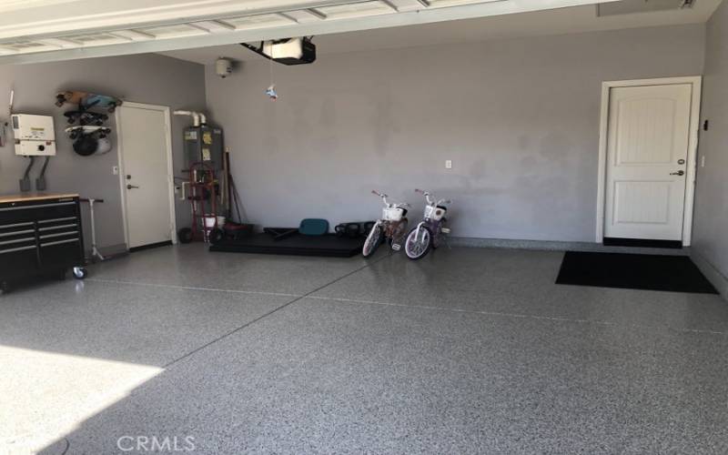 Garage with tankless water heater and door leading to side yard