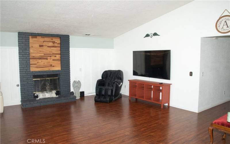 Living room showing fireplace with brick and custom wood facade in addition to laminate wood flooring and new paint.