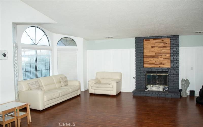 Living room showing fireplace with brick and custom wood facade in addition to laminate wood flooring and new paint.