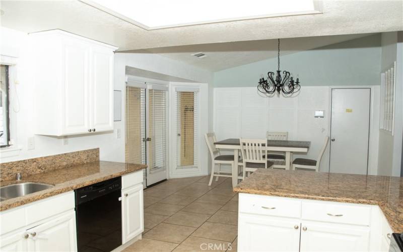 Kitchen with granite counters, modern white cabinets, tile floors, stainless steel appliances, breakfast bar, recessed lighting and pantry.