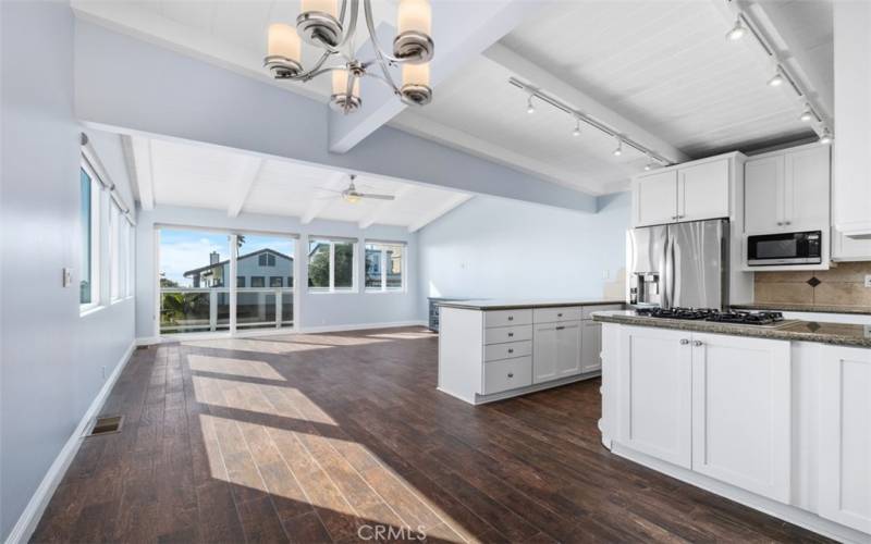 Open living, dining and kitchen space with modern wood-like tile flooring, ceiling fan and beamed ceiling