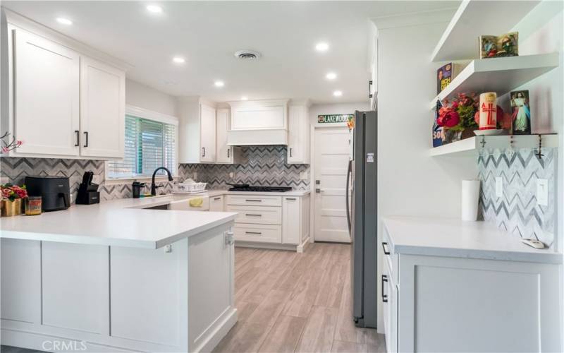 This view of the kitchen shows off the gorgeous counter tops and backsplash. The kitchen also has modern amenities and plenty of natural light.