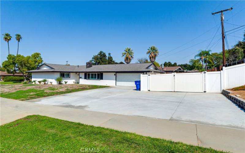 This is a front view of the property. It is located on a corner lot and has plenty of space for cars, including RV parking.