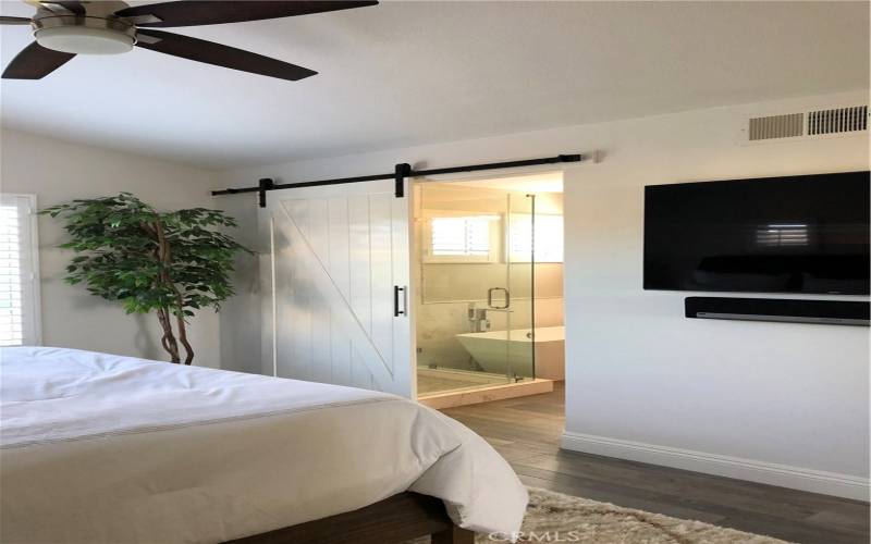 Master bedroom with Barn door open to custom shower, bath and walk in closet with built-ins.