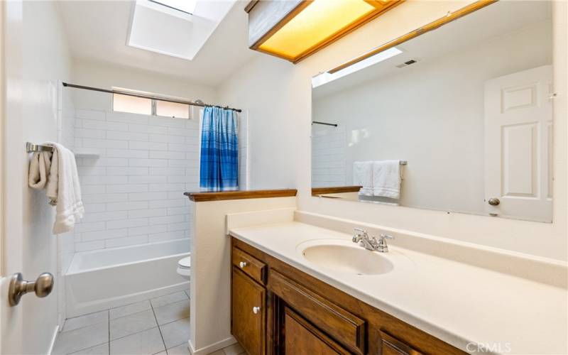 The bathroom offers a sizable vanity, attractive subway tile bathtub surround and a skylight.