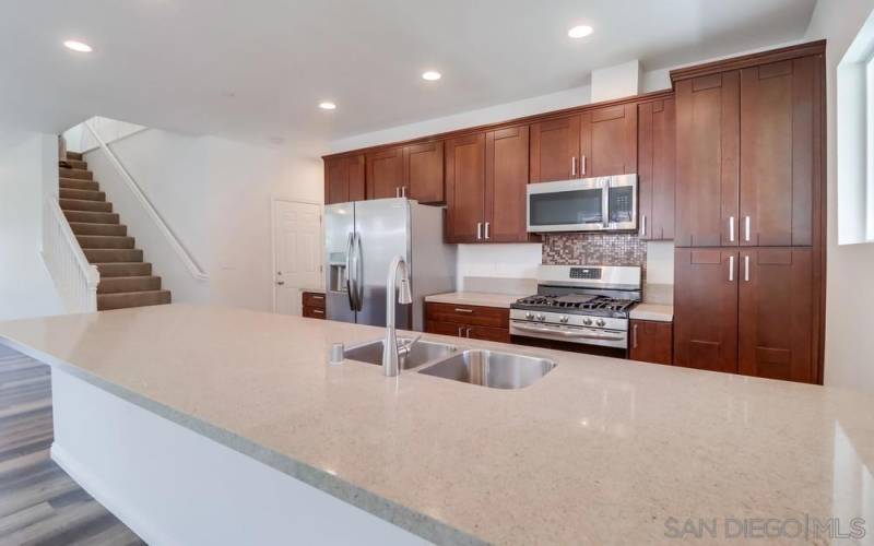 This brand new kitchen includes Quartz counters and there is room for four to cozy up to the kitchen to do homework or just chat while someone is making a meal.