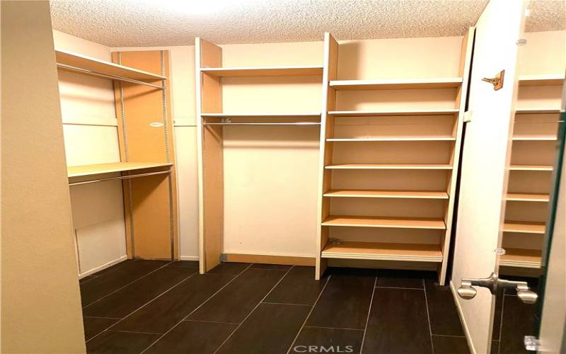 A walk in closet for the primary bedroom with all kinds of storage areas.