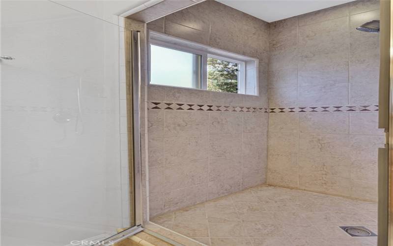 Primary suite shower room with a window to the secret garden area.