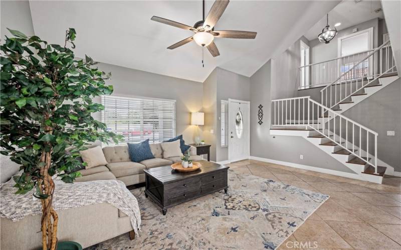 Living Room features tile floor, ceiling fan, blinds