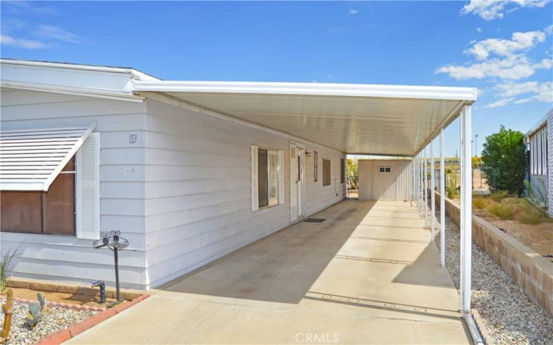 Another look at the level entry on the carport side and the 64' long covered carport parking for up to 3 cars. A handy shed is included.