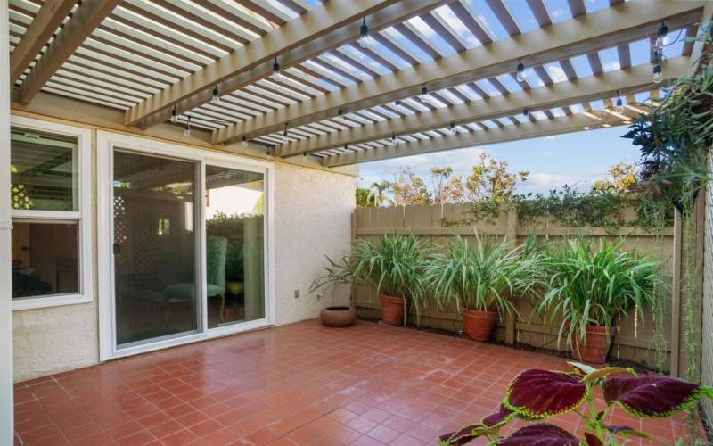 Beside the master bedroom, terracotta-tiled floor, sunlight filtering wooden pergola w/string lights