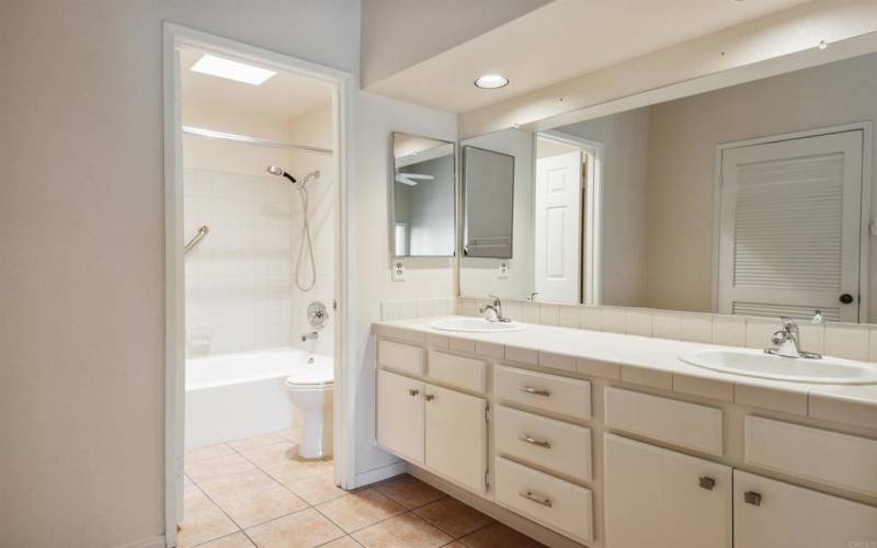 bathtub with skylight,  double sink, recessed lighting, large mirror