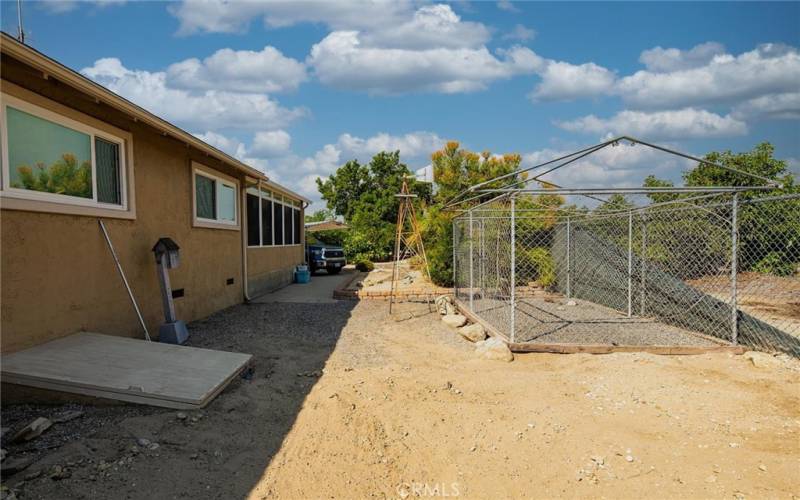 Side of home that has dog kennel and access to lit basement used for storage