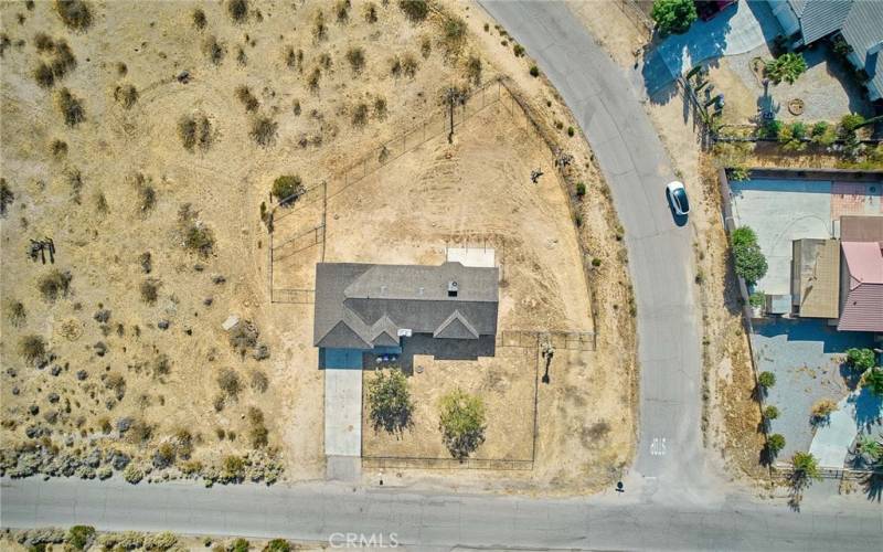 Aerial view of house on corner lot with fenced back and front yards.