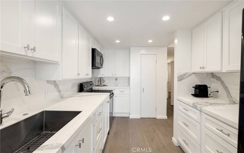 Kitchen features gleaming countertops and contemporary backsplash