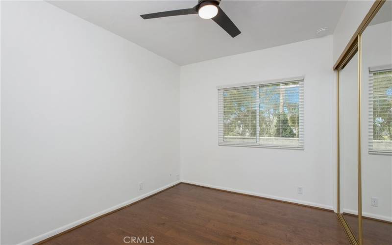 guest bedroom. mirrored closet doors, ceiling fan