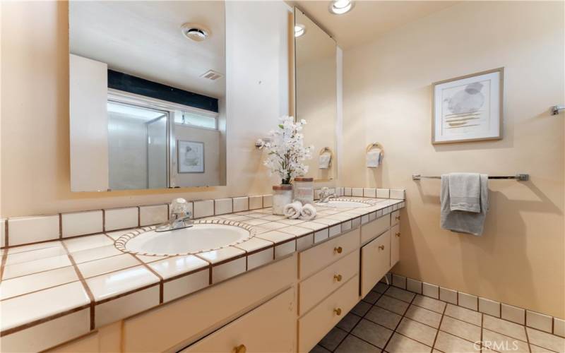 Primary en suite with double sinks, tiled counter and flooring.