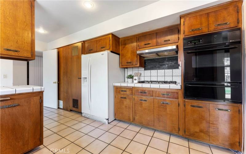 Water heater in closet adjacent to the refrigerator. Plenty of cabinets and tiled counters/flooring. Built in oven and gas stove top.