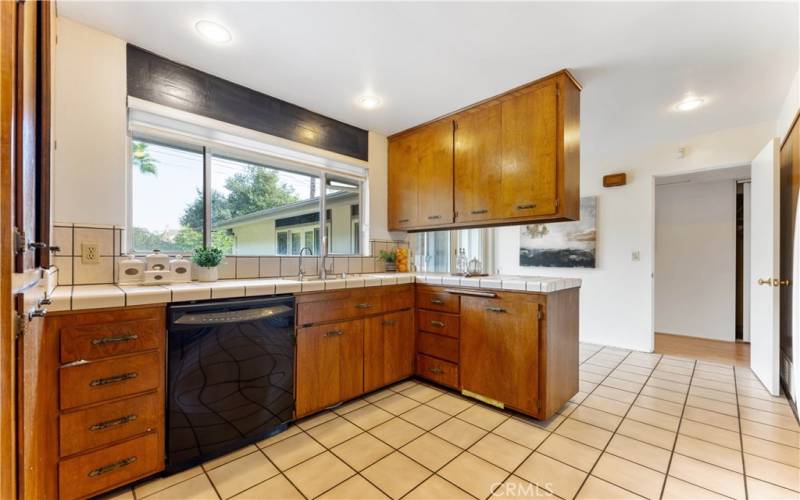 Original cabinets of the mid century kitchen. Large window view of backyard. Peninsula counter/cabinets with space on the either side for casual dining area.